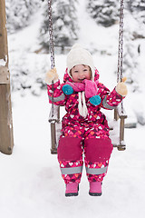 Image showing little girl at snowy winter day swing in park