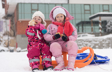 Image showing portrait of two little grils sitting together on sledges