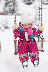 Image showing little girl at snowy winter day swing in park