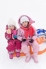 Image showing portrait of two little grils sitting together on sledges