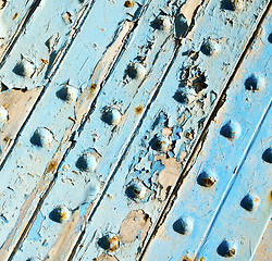 Image showing stripped paint in the blue wood door and rusty nail