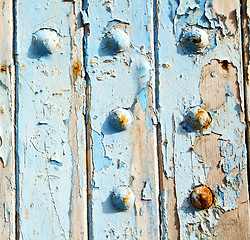 Image showing stripped paint in the blue wood door and rusty nail