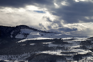 Image showing Village in winter mountains and storm clouds at evening