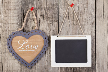 Image showing Empty wooden blackboard sign and heart shape frame 