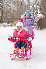 Image showing The girls in the courtyard of riding a snow sled rejoice