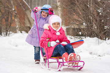Image showing The girl rolls the other girl on a sled in the yard