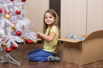Image showing Funny girl takes off a Christmas tree with toys