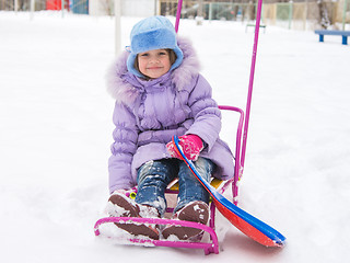 Image showing Joyful girl sitting on a sled in the snowy weather