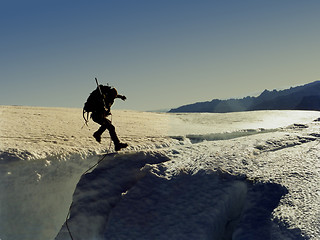 Image showing Climber jumping a crevasse