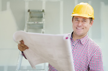 Image showing Contractor Holding Blueprints Inside Home Construction Site