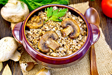 Image showing Buckwheat with champignons in clay bowl on table