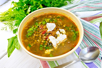 Image showing Soup lentil with spinach and cheese in yellow bowl on board