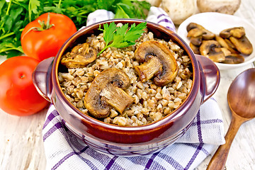 Image showing Buckwheat with champignons in clay bowl on napkin