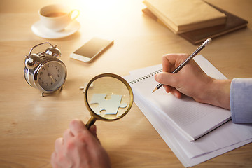 Image showing The male hands with a pencil and magnifying glass