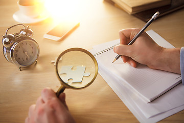 Image showing The male hands with a pencil and magnifying glass