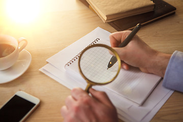 Image showing The male hands with a pencil and magnifying glass