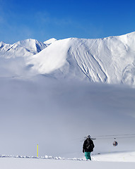 Image showing Snowboarder on off-piste slope and mountains in mist