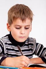 Image showing Cute schoolboy is writting