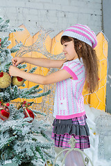 Image showing Little girl  is decorating christmas tree