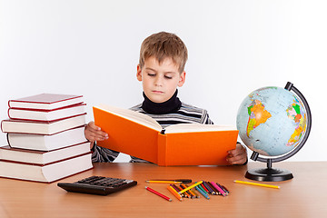 Image showing Cute schoolboy is reading a book