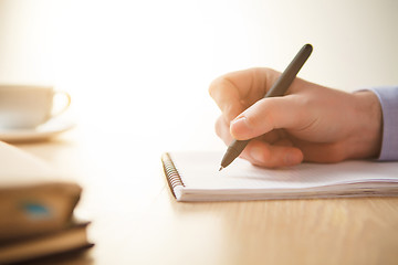 Image showing The male hand with a pen and the cup