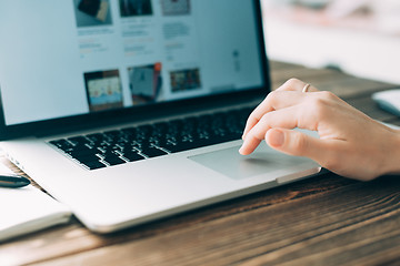 Image showing Woman working with laptop placed on wooden desk