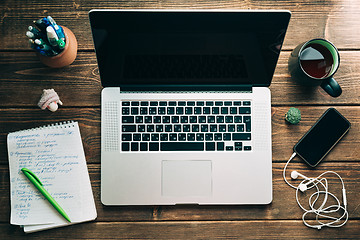 Image showing Workplace with open laptop on modern wooden desk 