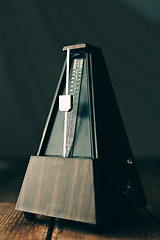 Image showing Vintage metronome, on a dark background.