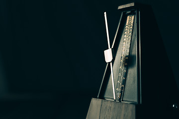 Image showing Vintage metronome, on a dark background.