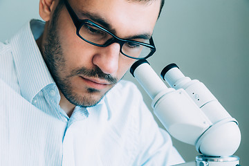 Image showing Young male doctor viewing through microscope