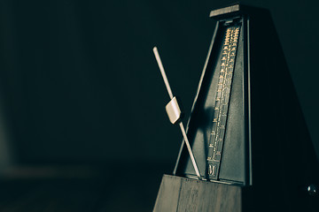 Image showing Vintage metronome, on a dark background.