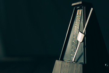 Image showing Vintage metronome, on a dark background.