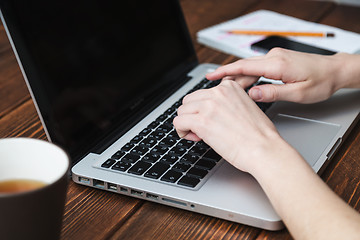 Image showing Woman working with laptop placed on wooden desk