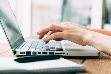 Image showing Woman working with laptop placed on wooden desk