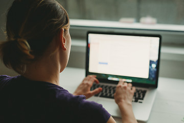 Image showing Woman working with laptop placed on wooden desk