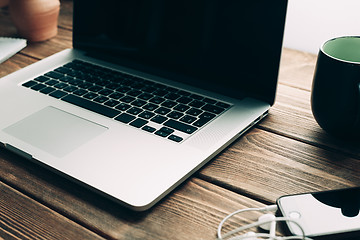 Image showing Workplace with open laptop on modern wooden desk 