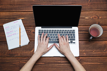 Image showing Woman working with laptop placed on wooden desk