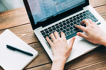 Image showing Woman working with laptop placed on wooden desk