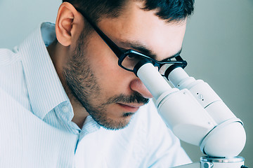 Image showing Young male doctor viewing through microscope