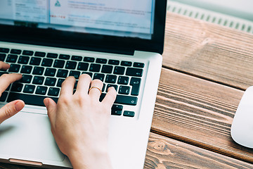 Image showing Woman working with laptop placed on wooden desk