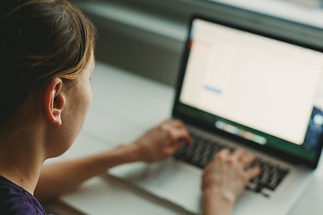 Image showing Woman working with laptop placed on wooden desk