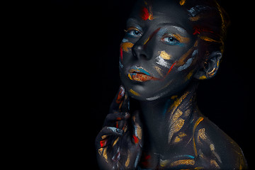 Image showing Portrait of a young woman who is posing covered with  black paint 