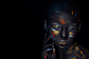 Image showing Portrait of a young woman who is posing covered with  black paint 