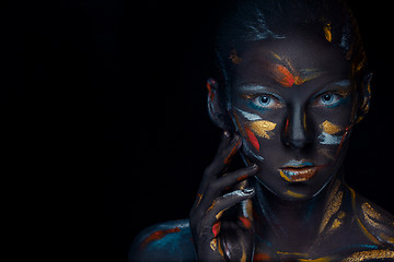 Image showing Portrait of a young woman who is posing covered with  black paint 