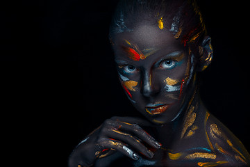 Image showing Portrait of a young woman who is posing covered with  black paint 