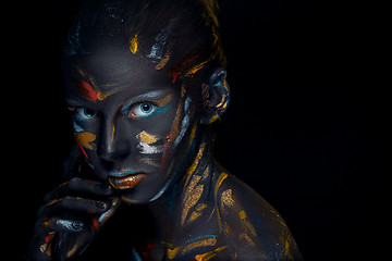 Image showing Portrait of a young woman who is posing covered with  black paint 