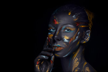 Image showing Portrait of a young woman who is posing covered with  black paint 