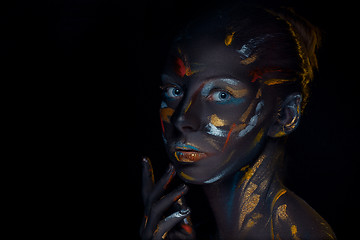 Image showing Portrait of a young woman who is posing covered with  black paint 