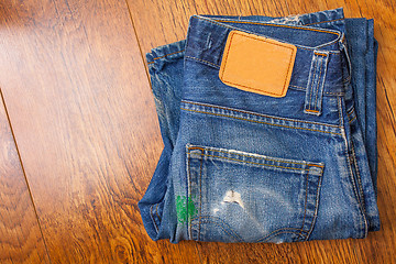 Image showing old blue jeans with brown label on the belt smeared with green p