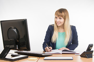 Image showing Business woman writing in a business book and looked at the computer monitor